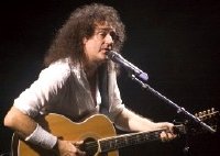 Brian May playing an acoustic guitar