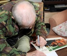 Alan Sillitoe signing a lobby card from 'Saturday Night and Sunday Morning'